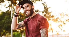 a person smiling and holding the brim of their hat