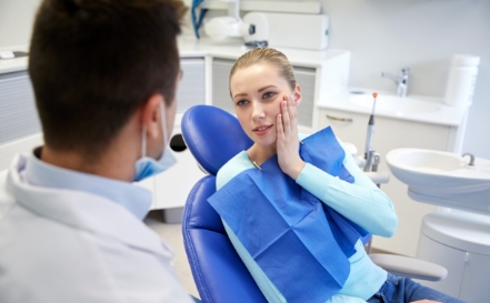 Woman in need of emergency dentistry holding cheek in pain