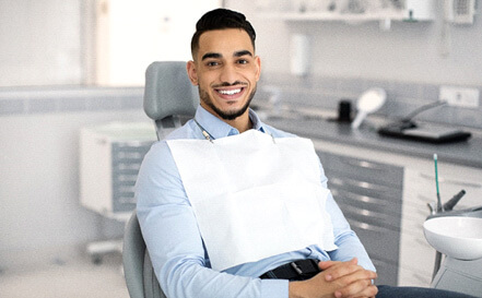 male dental patient smiling with hands folded