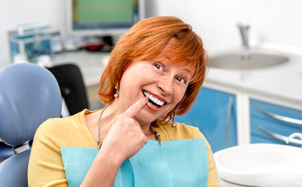 female dental patient pointing to her smile