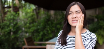 Woman in need of wisdom tooth extraction holding jaw in pain