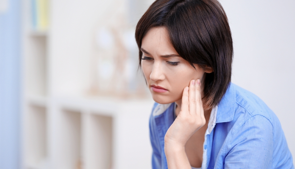 Woman in need of T M J therapy holding jaw in pain