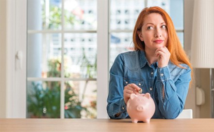 Woman putting a coin into a piggy bank