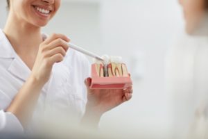 dentist showing a patient a model of a dental implant 