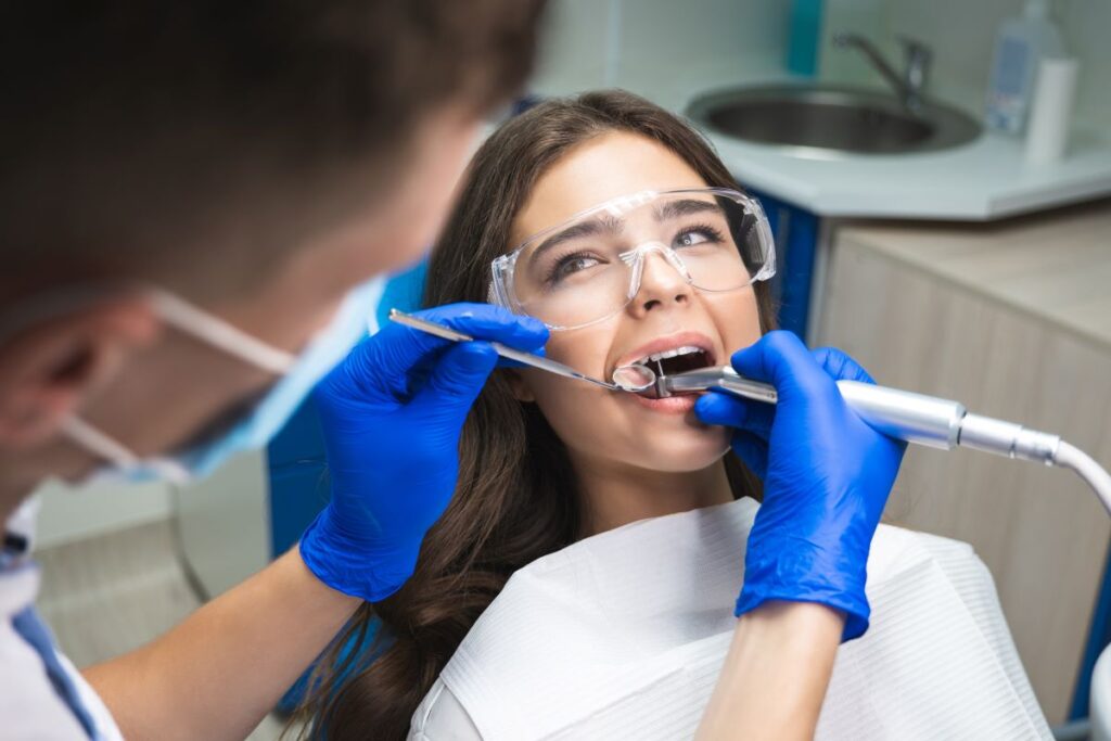 A woman in a dentists chair with dental tools in her mouth